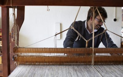 Man handweaving textiles at loom