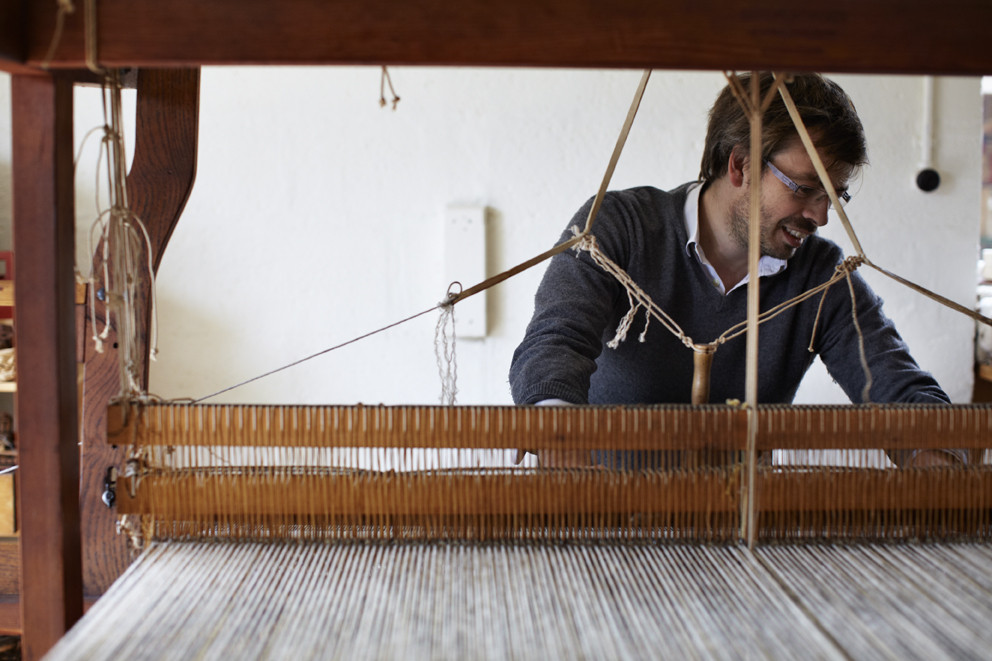 Man handweaving textiles at loom